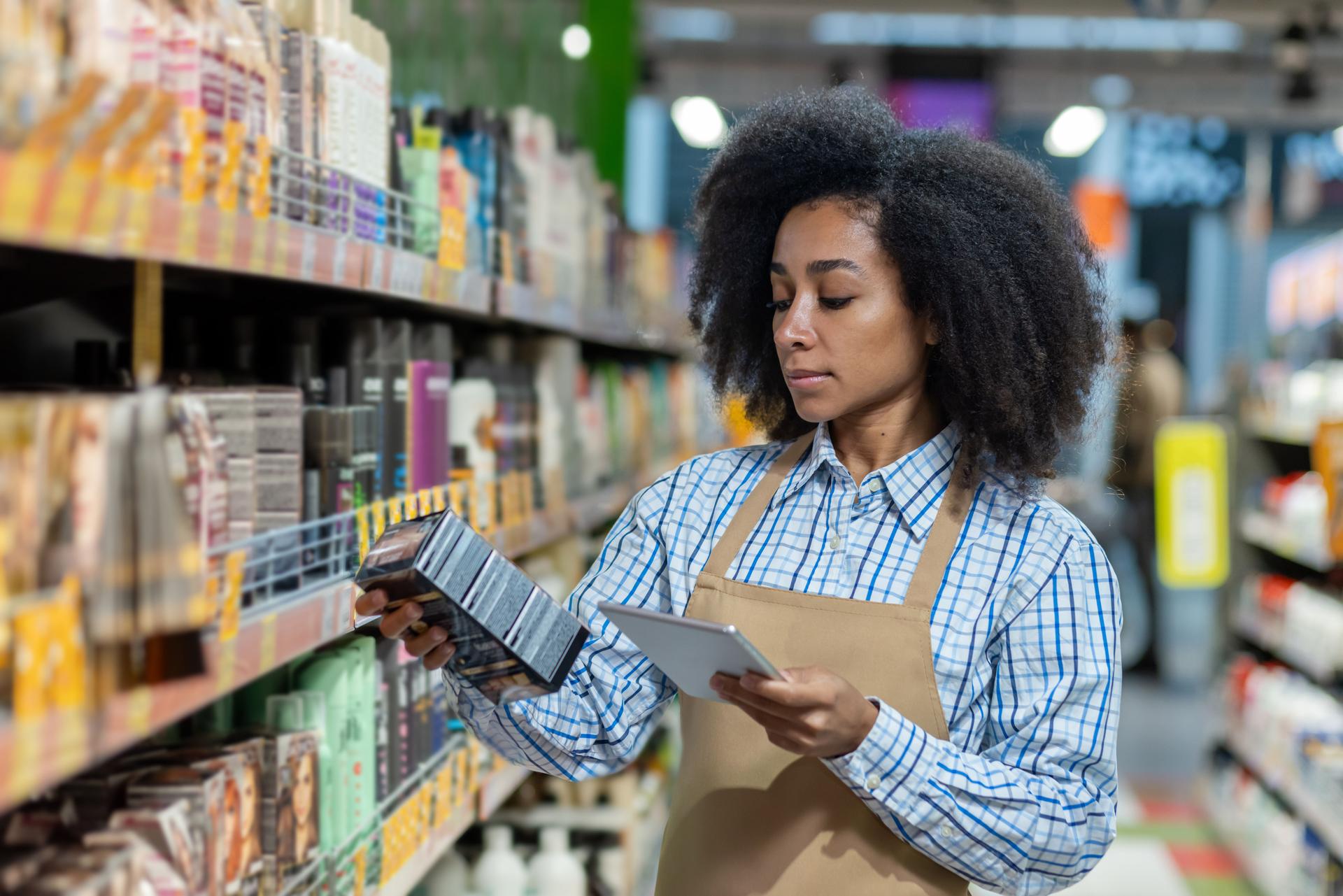 Store employee checking inventory and scanning product with digital tablet in beauty supply aisle