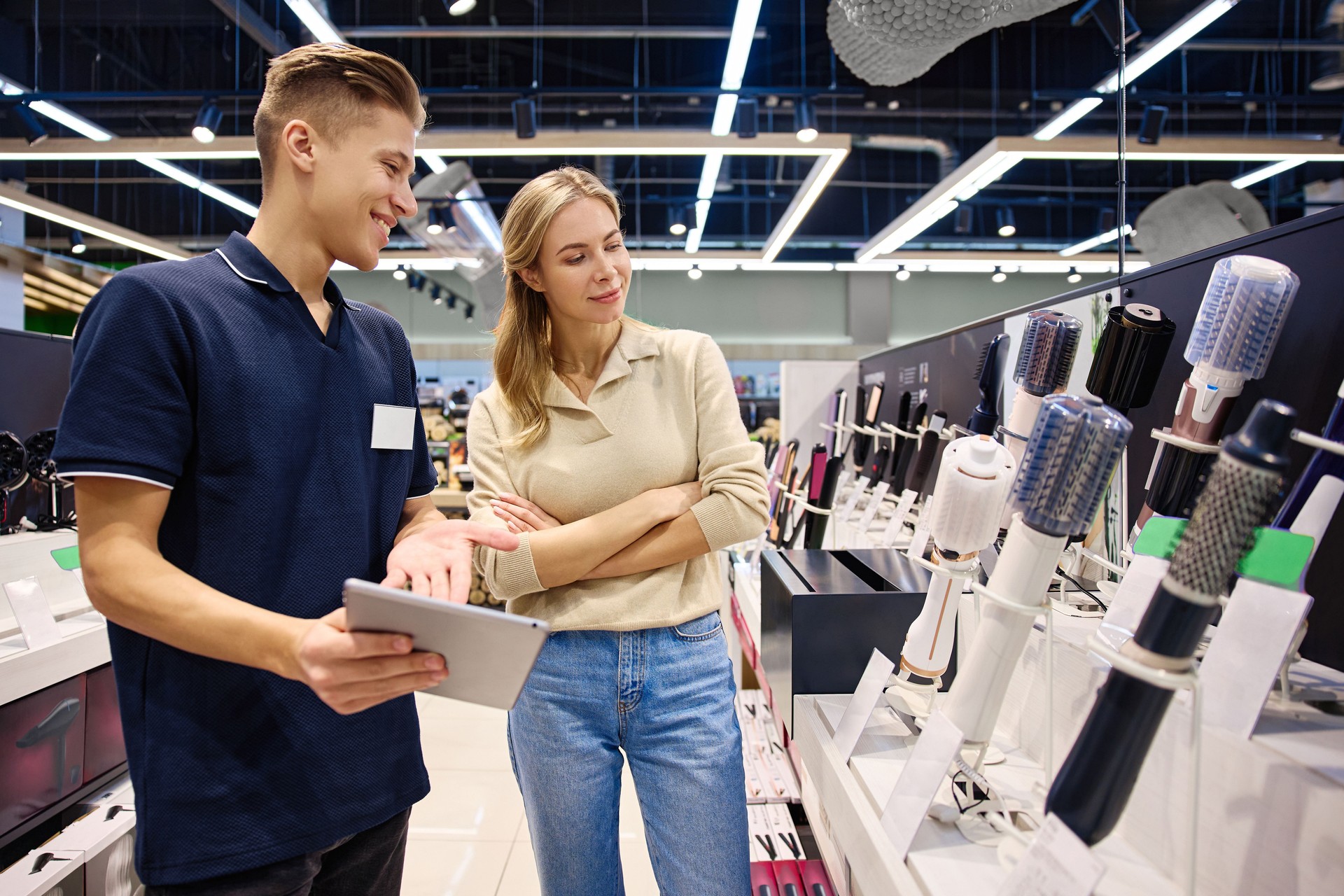 A customer talks with a salesperson about hair styling products and trends in a store